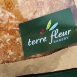 A green Terre Fleur Bakery sticker on a fresh baked sourdough bread package.