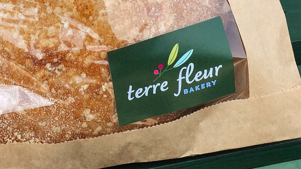 A green Terre Fleur Bakery sticker on a fresh baked sourdough bread package.