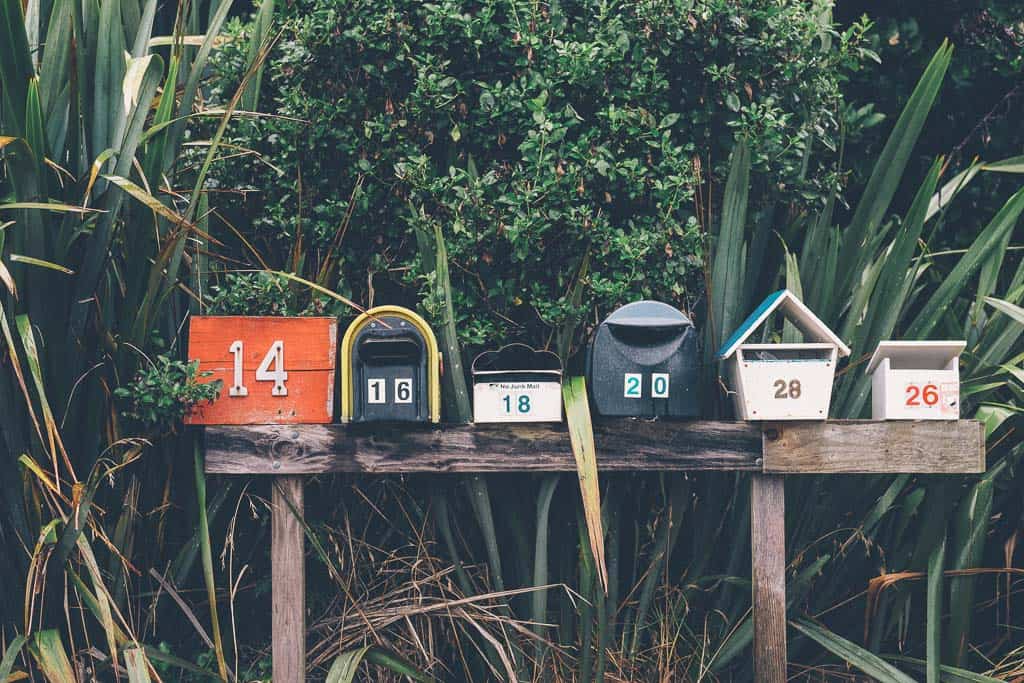 row of mailboxes in front of greenery